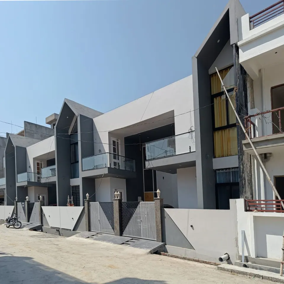 Angled street view of the row houses: grey gabled frames, white volumes, glass balconies and patterned grey boundary walls