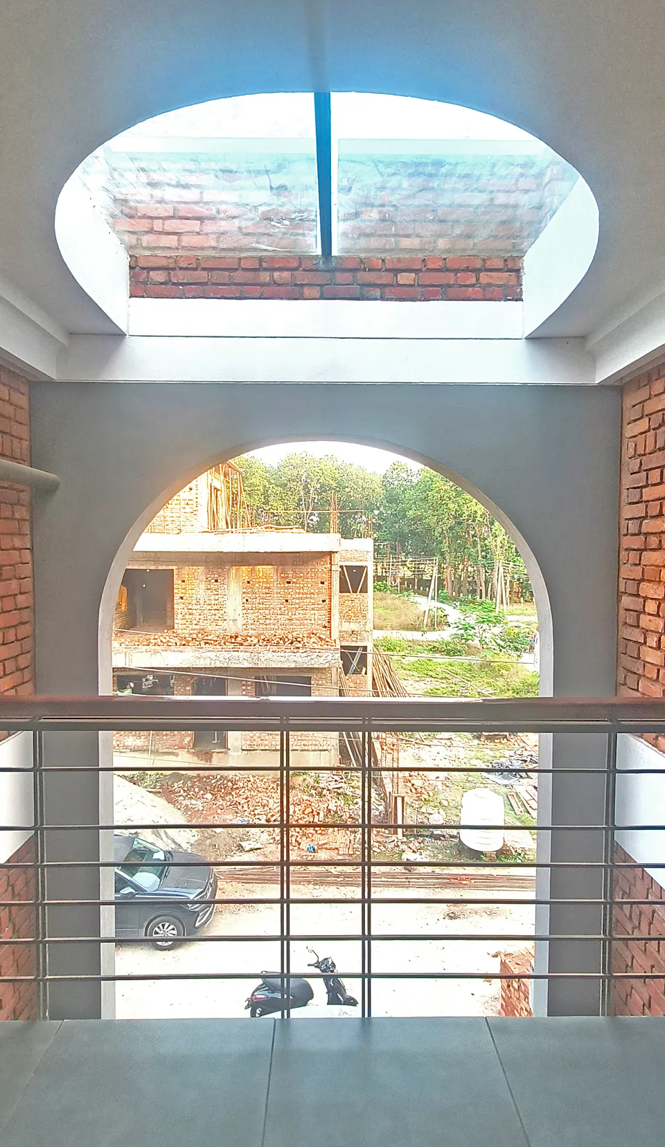 View out through the grey arch from an upper landing, an oval skylight overhead and a steel railing