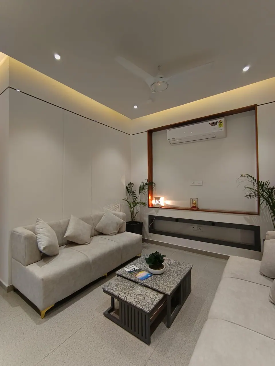 Lounge corner with pale grey sofas, stone-topped nesting tables and a timber-framed niche
