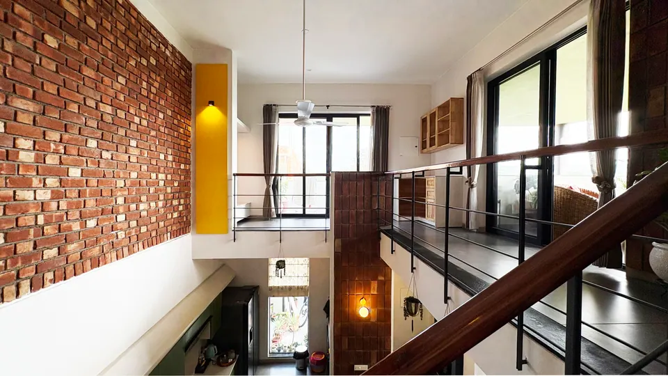 Upper landing with a timber-railed gallery over the double-height space, a brick wall and a yellow-lit slot