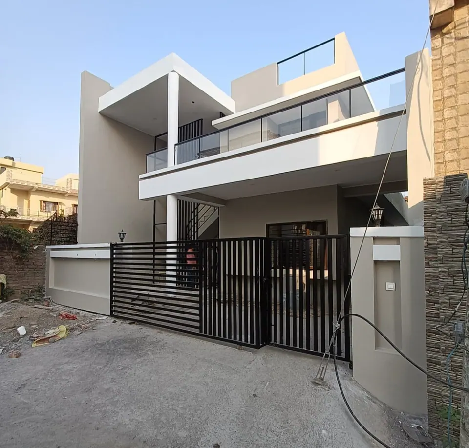 Angled street view: a white cantilevered canopy, glass balcony railings, a black bar gate and a rooftop room