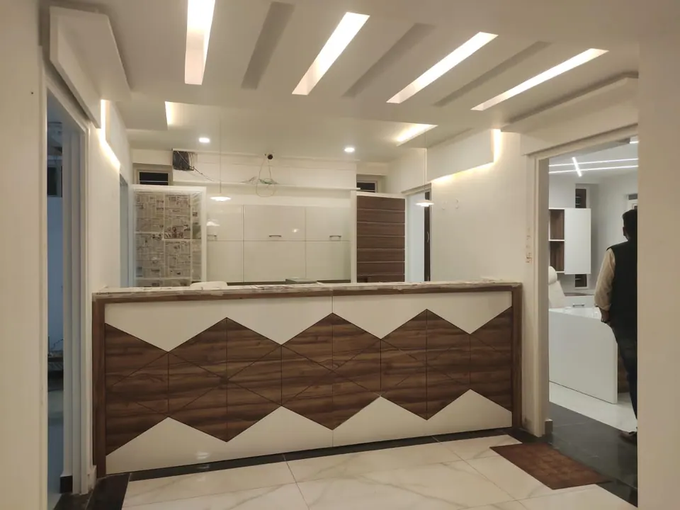 Counter faced with timber and white zigzag panels below linear ceiling lights, white cabinets behind and a cabin beyond