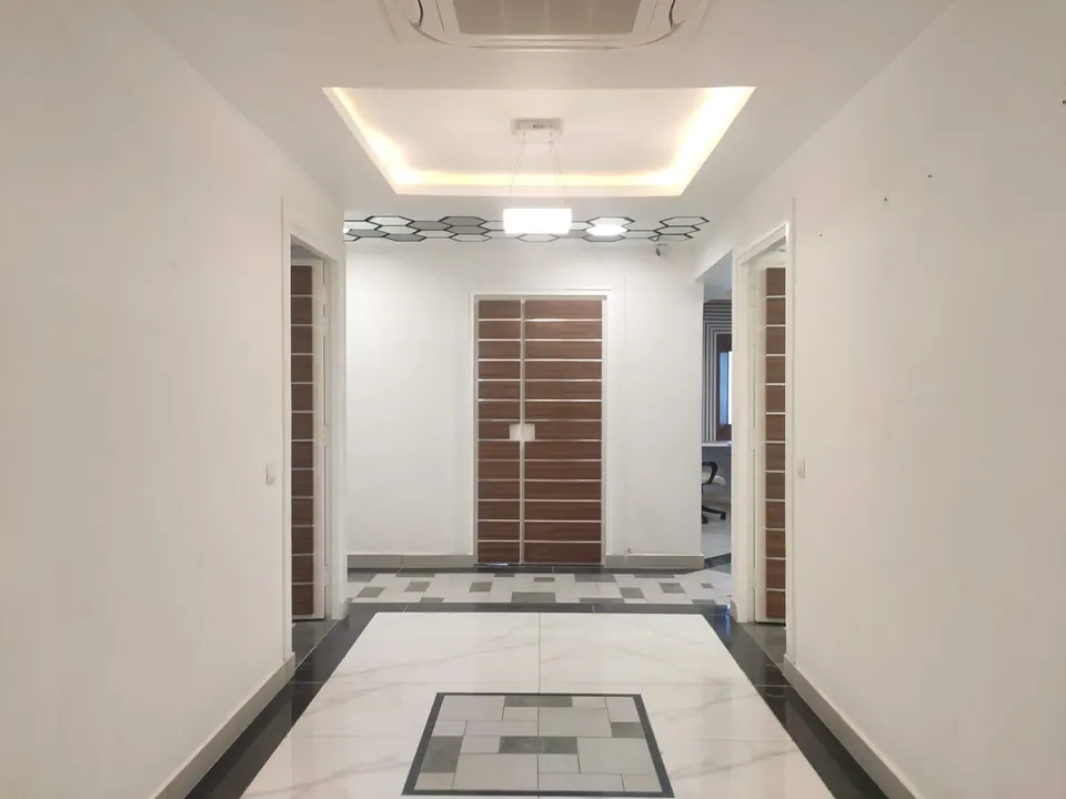 Lobby with a marble floor inlay, timber-striped double doors and a coffered ceiling with a cove light