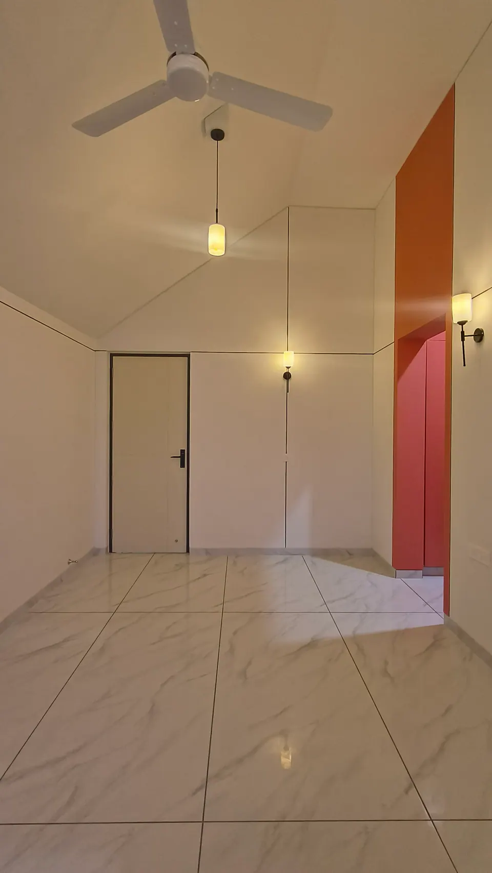Room under a gabled ceiling with a fan and pendant, a white door and a coral-red wardrobe niche