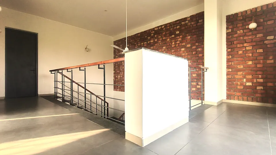 Upper landing with a dark door, a stair rail around the void and an exposed brick wall