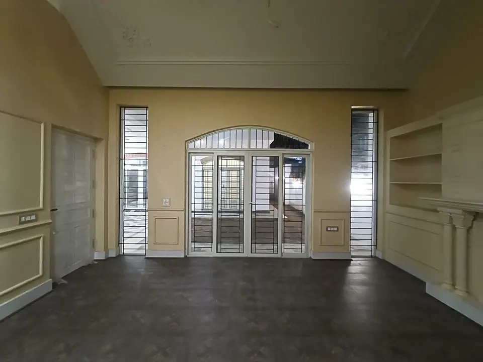 Pale yellow room with moulded wall panels, an arched glazed door between tall slit windows and a fireplace with shelves
