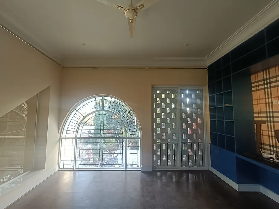 Room with an arched grille window, a glazed door with jali panels and built-in blue shelving