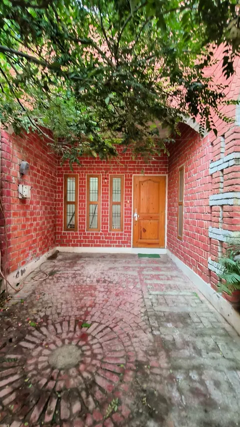 Forecourt with a circular brick-paving pattern between red brick walls, leading to the timber front door
