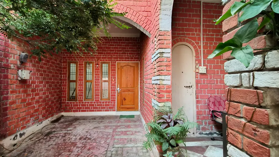 Forecourt of red brick with white-pointed joints: a timber door and three slim windows under a brick arch, and an arched side door