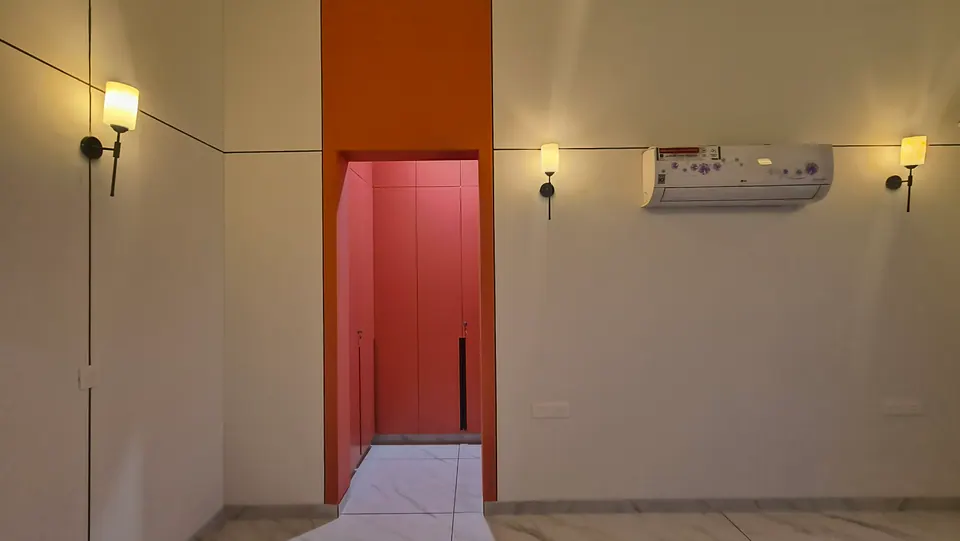 Bedroom wall with a coral-red wardrobe niche between wall lamps, an air conditioner above
