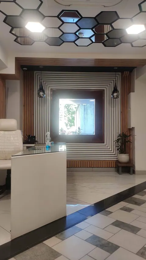 Desk before the black and white striped feature wall with its timber-lined window, under the hexagonal ceiling