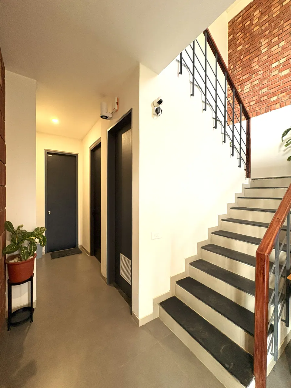 Hallway with dark doors beside a stair with slate-faced treads, steel balusters and a timber handrail