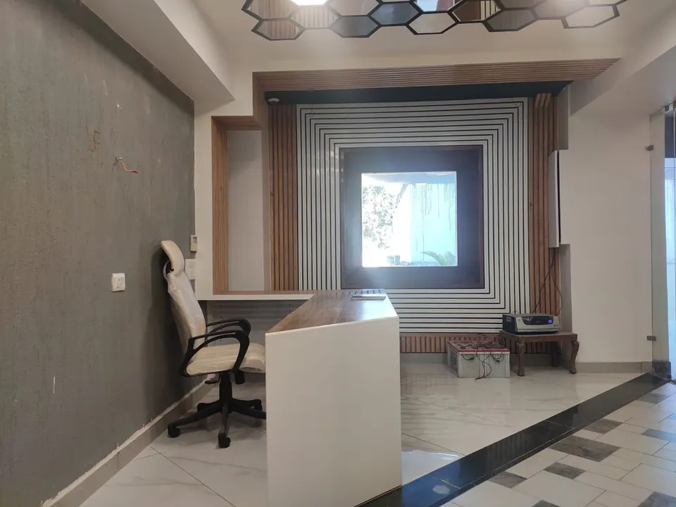 Office corner with a white desk and chair before a black and white striped wall framing a timber-lined window