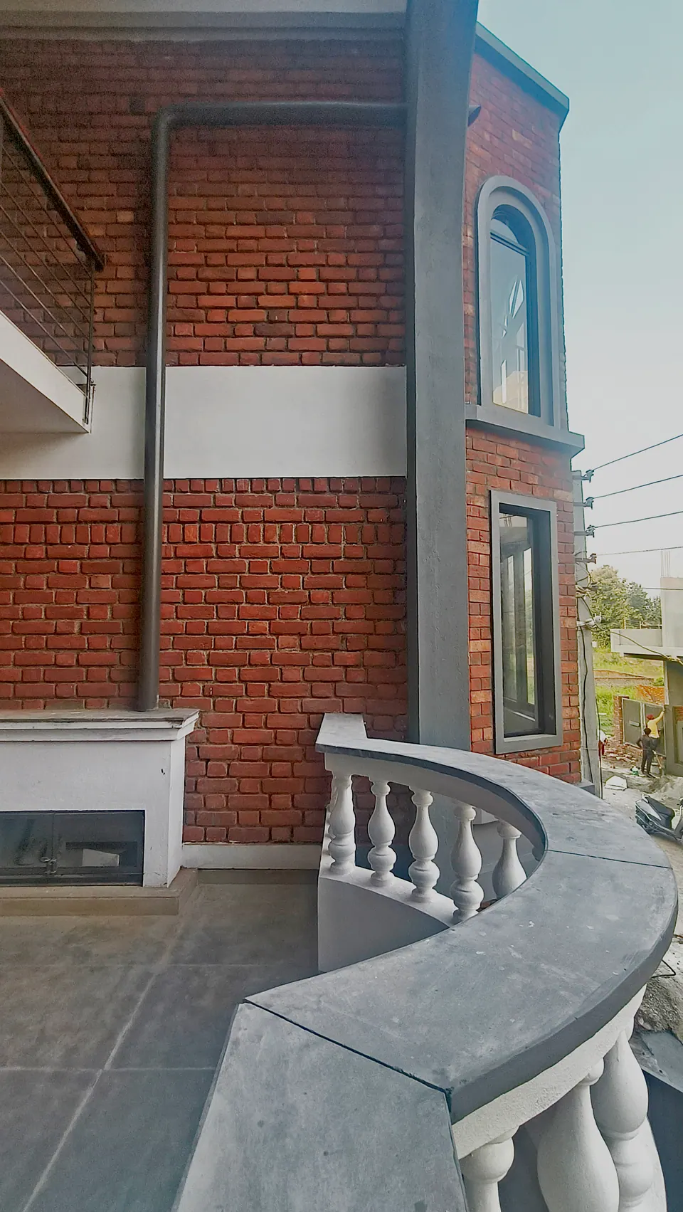 Front balcony with a curved white balustrade, brick walls and the edge of the grey arch