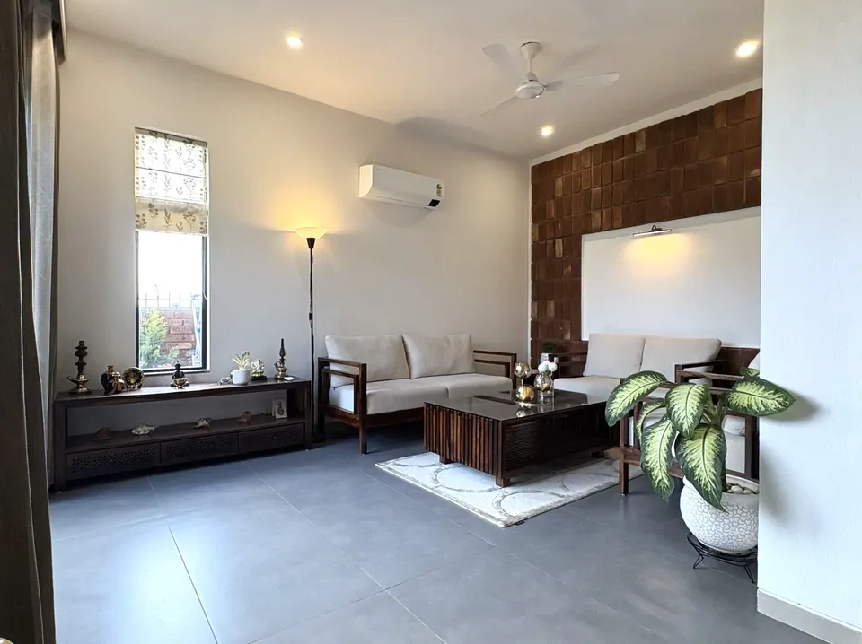 Living room with a brick-tile wall alcove, cream sofas, a low timber console with brass objects and a potted plant