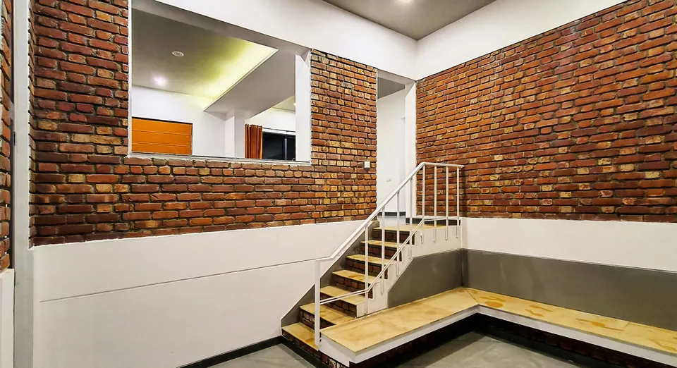 Exposed brick wall with an opening to the kitchen, above a short stair and a timber-topped platform