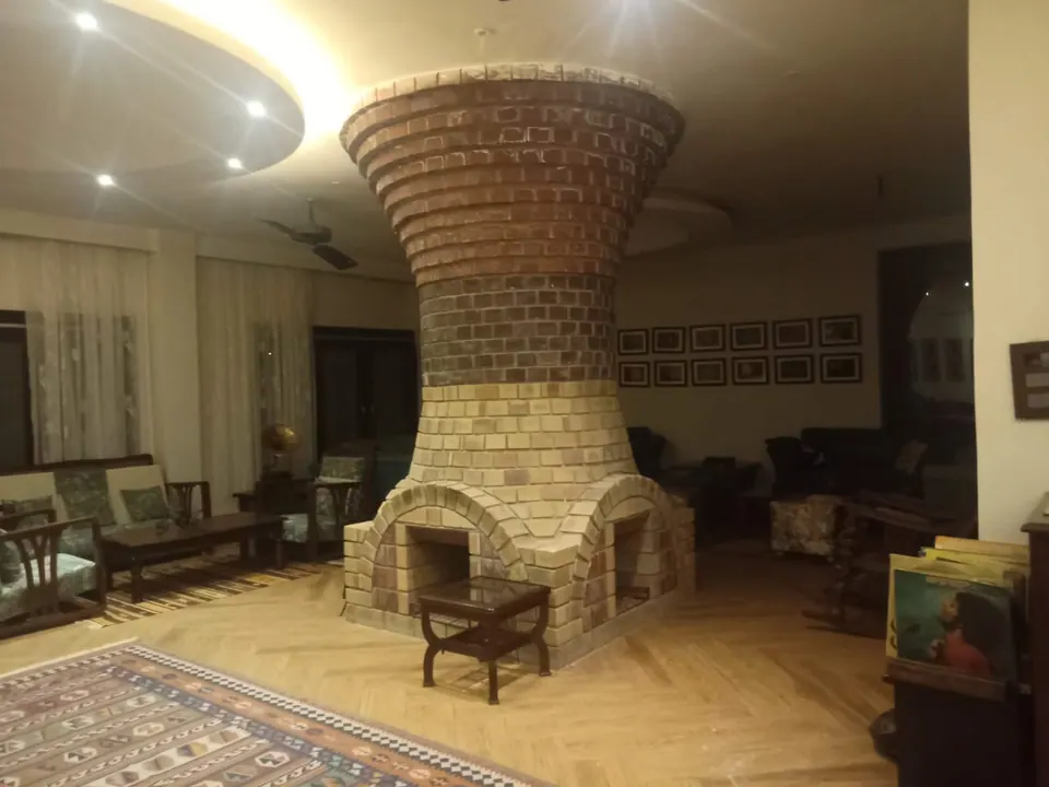 Hourglass-shaped brick chimney, dark brick above and pale brick with arched fireplaces below, in a sitting room