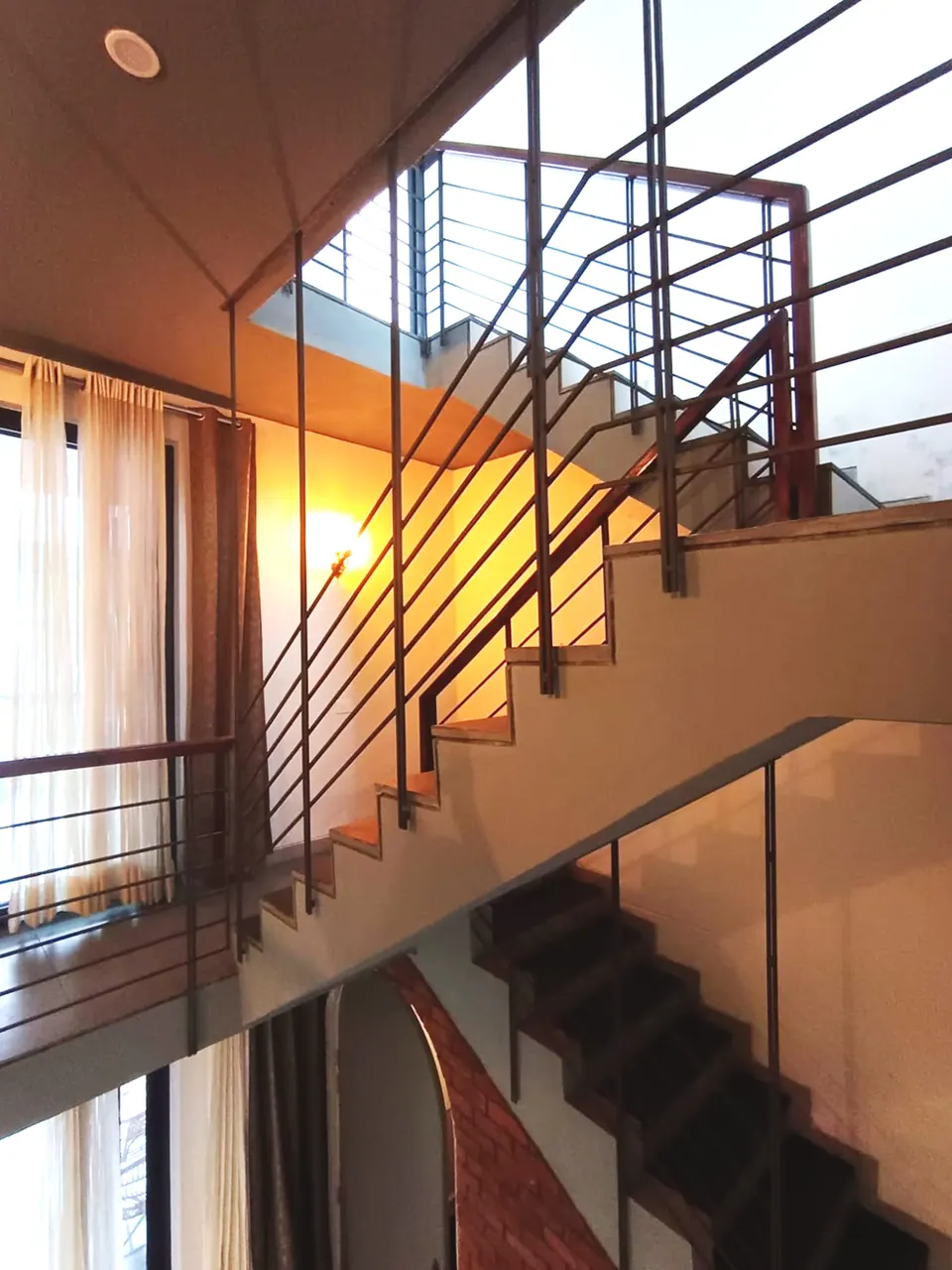 Stair with black steel railings and timber handrails rising through warm-lit floors