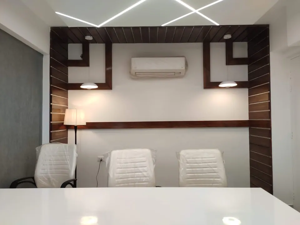 Meeting cabin: three white chairs at a white table before a timber-framed wall with pendant lights and a floor lamp