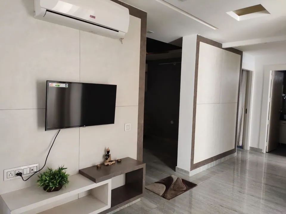 Cabin with a wall-mounted screen above a white and timber console, an air conditioner and a doorway to the corridor