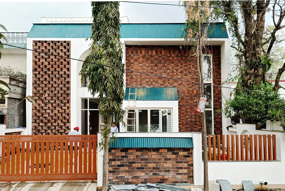 Front elevation: brick jali panels and exposed brick between white frames, turquoise canopies and red slatted fencing