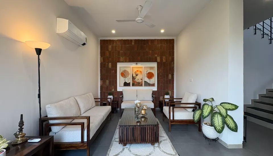 Living room with cream sofas in dark timber frames, a slatted coffee table and a brick-tile feature wall with a triptych