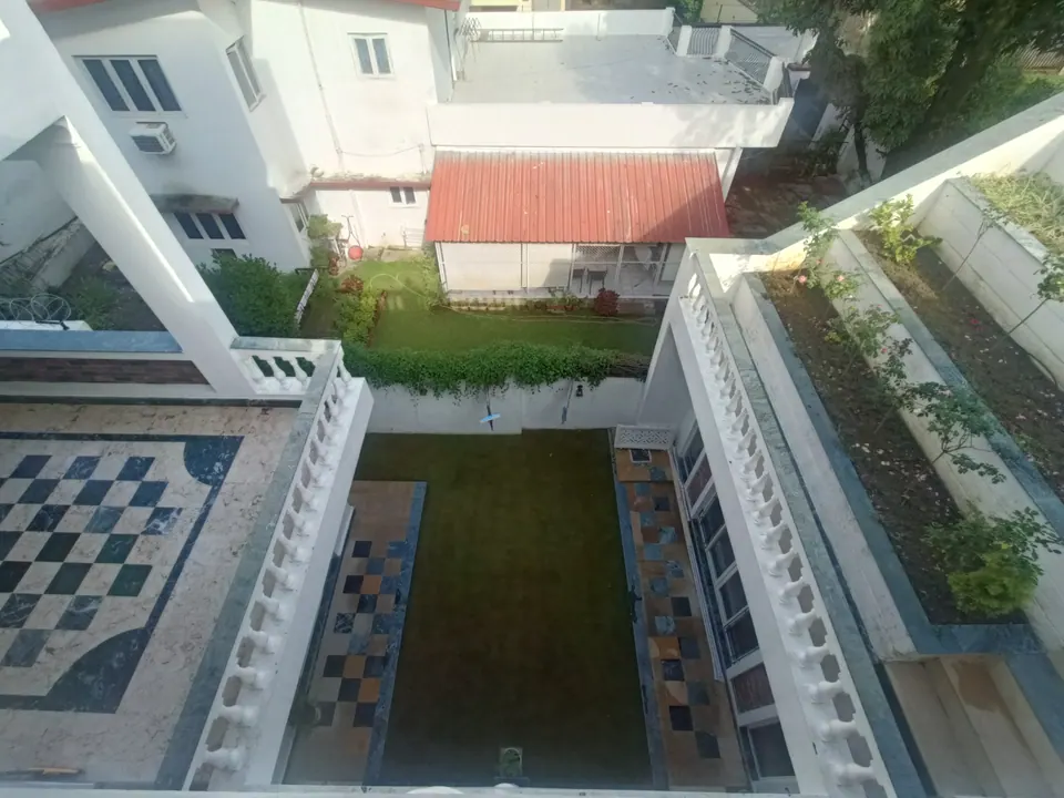 Looking down into the courtyard: a lawn with chequered stone borders between white balustrades and planted terraces