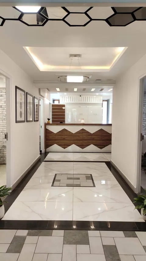 Corridor with a marble floor and tile inlay leading to the zigzag-panelled counter, prints along the wall