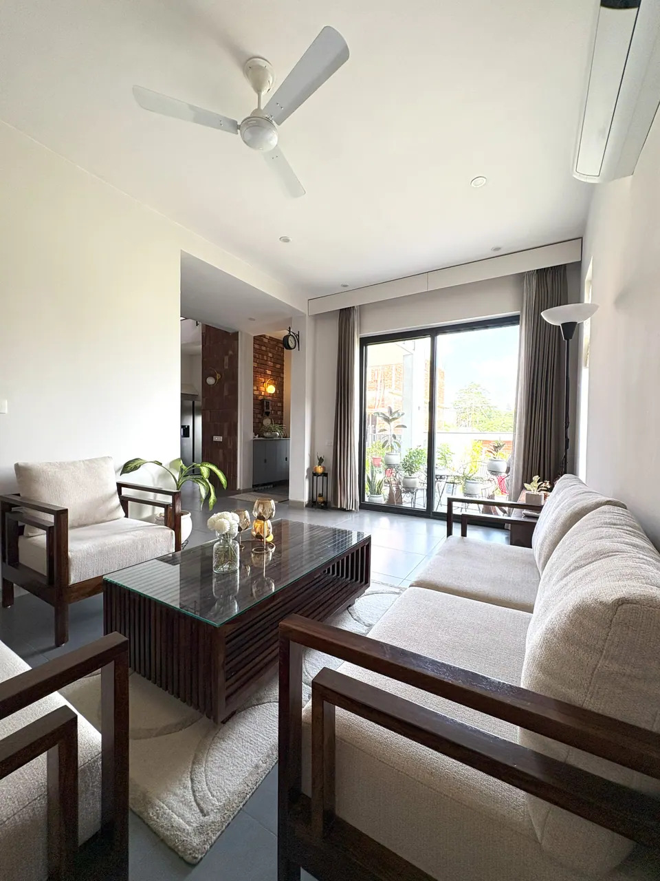 Living room with cream sofas around a glass-topped slatted table, a sliding door to the terrace beyond