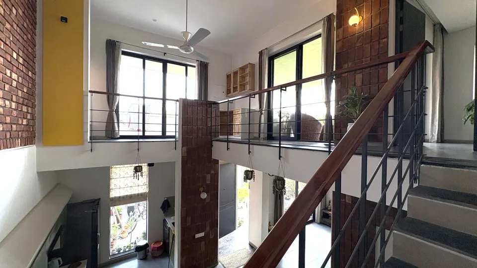 Stair with a timber handrail rising to the upper gallery, with brick walls, a yellow slot and tall windows