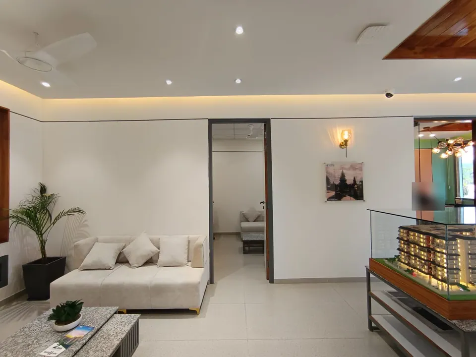 Waiting area with a white sofa and stone-topped table beside a glass-cased model of the apartment blocks