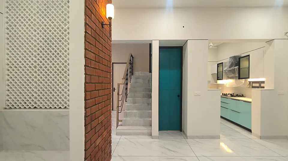 White lattice screen and brick pier framing a view to the stair, a teal door and the kitchen