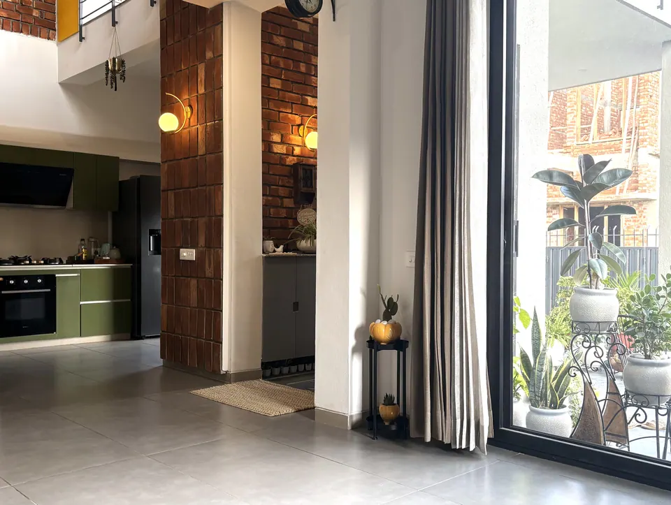 Hall with a brick-tile column and globe wall lights, the green kitchen behind and a sliding door to the patio