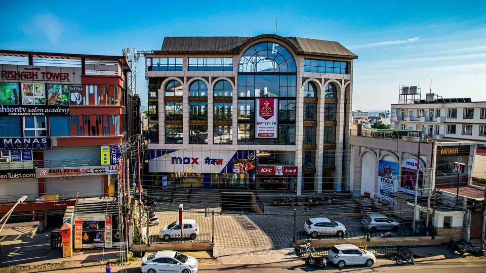 Street view of the stone-clad commercial block with arched windows between neighbouring buildings, cars in the forecourt