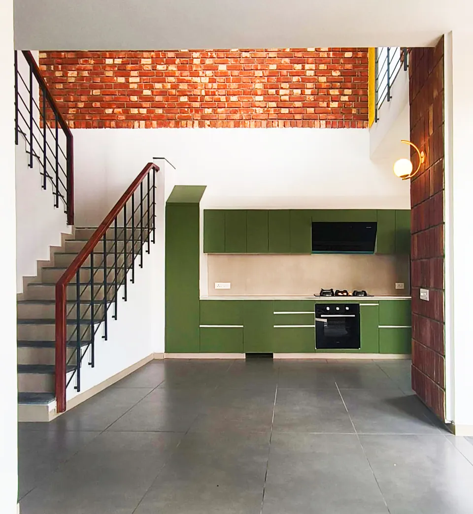 Stair rising beside the green kitchen under a brick band, a brick-tile column with a globe light at the right