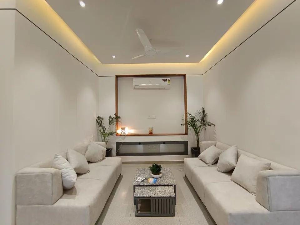 Lounge with two white sofas facing across a stone-topped table, a timber-framed niche and palms
