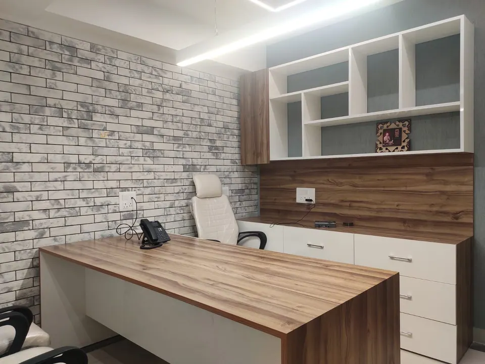 Cabin with a timber and white desk, a white chair, open shelving and a brick-effect wall under a linear light