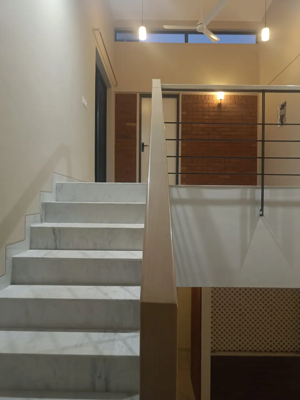 Marble stair to an upper landing with exposed-brick walls, clerestory windows and lamps