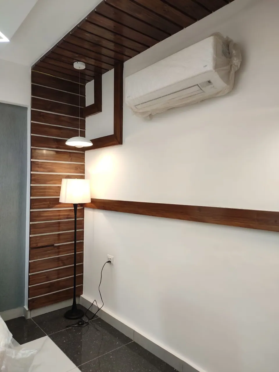 Cabin corner with a timber-slatted wall and ceiling band, an air conditioner and a floor lamp