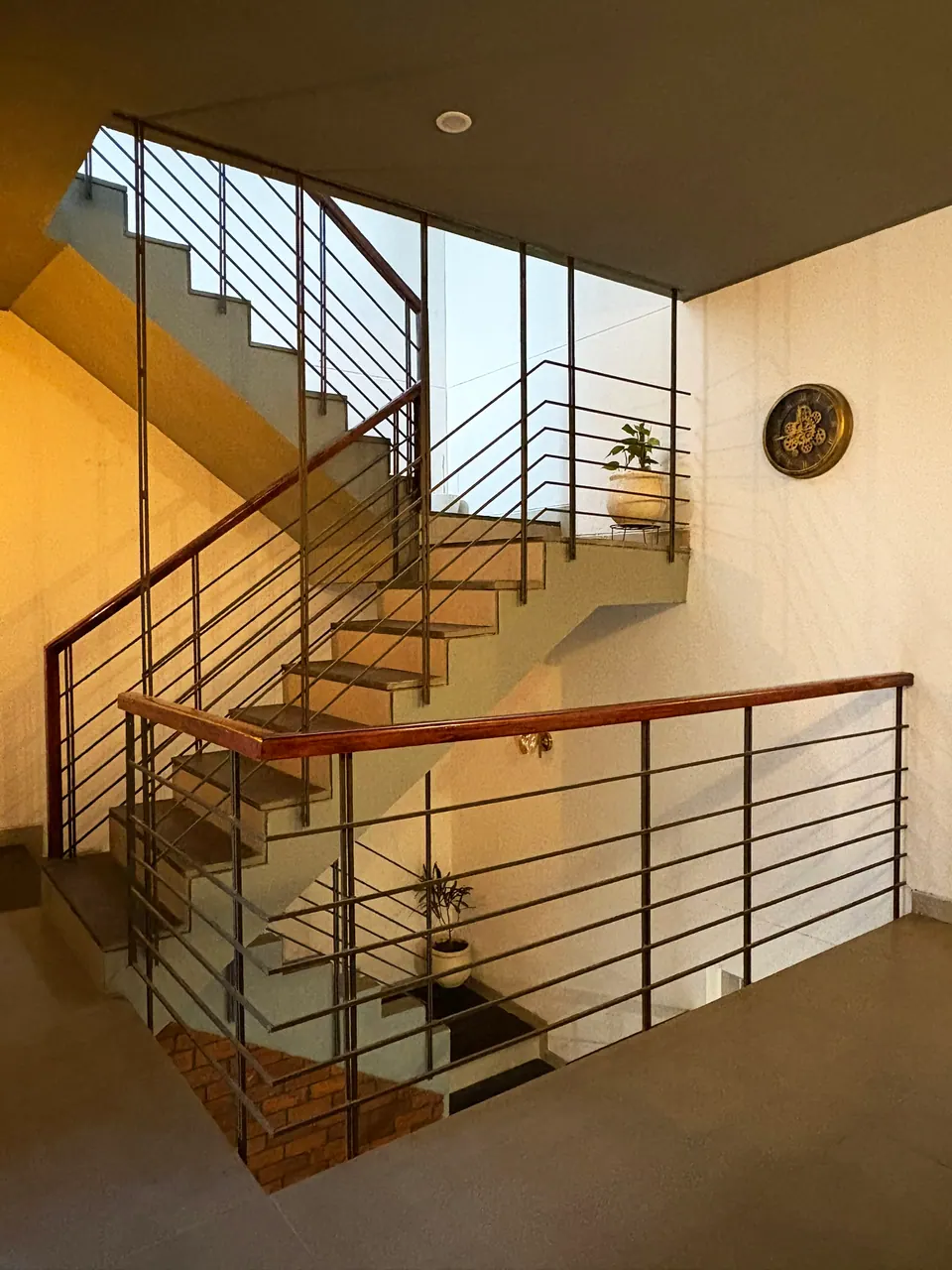 Looking down a stairwell: a timber-tread stair with black steel railings and a decorative plate on the wall