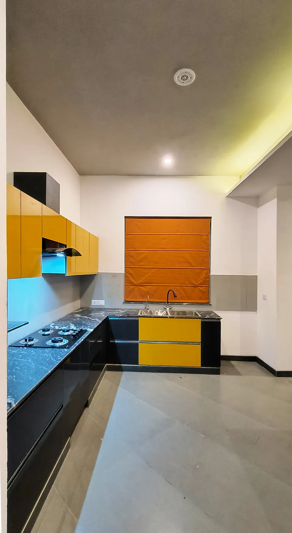 L-shaped kitchen with yellow and black cabinets and an orange blind over the window