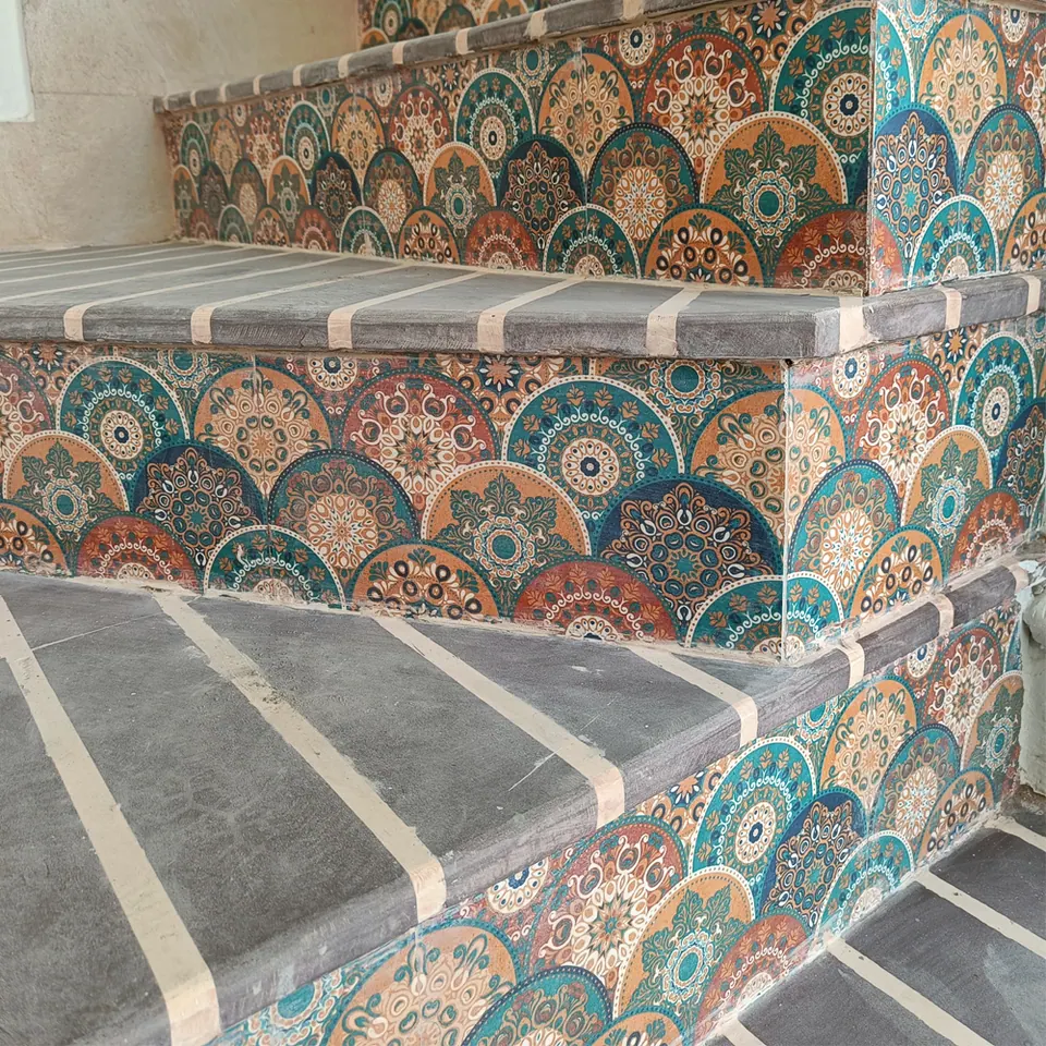 Stair risers clad in teal, orange and blue patterned tiles below grey stone treads